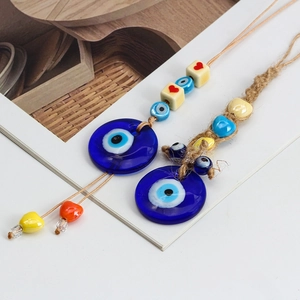 Close-up of glass Evil Eye charms with colorful beads and woven ropes on wood tray