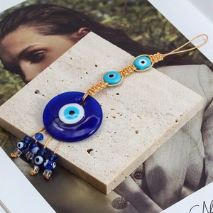 Detailed view of Evil Eye glass pendant with woven rope and blue tassel decoration