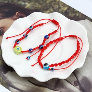 Handmade red braided Evil Eye bracelets with adjustable cords in a white ceramic dish