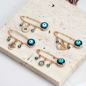 Gros plan détaillé de broches épingles à nourrice Evil Eye dorées avec breloques Main de Hamsa