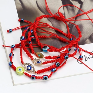 Detail of red braided bracelets with Hamsa Hand charms and glass Evil Eye beads