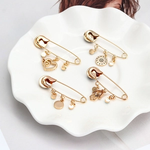 Détail de 4 broches épingles dorées avec pendentifs en forme de cœur et main de Fatima