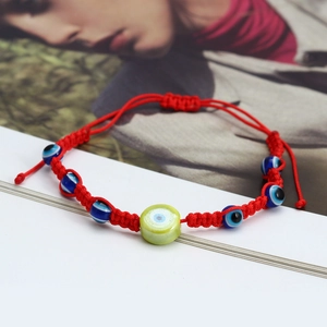 Detail of handmade red woven Evil Eye bracelet featuring blue beads and adjustable closure
