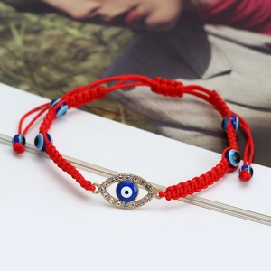 Macro shot of red braided string bracelet with evil eye charm and sparkling crystals