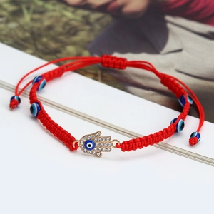 Detail of red woven bracelet with Hamsa Hand pendant and blue Evil Eye charms