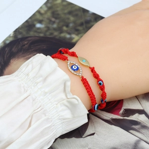 Close-up of red braided Evil Eye bracelets with crystals and beads worn on wrist