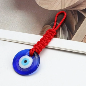 Close-up of Turkish Evil Eye charm with red braided cord and blue glass pendant detail