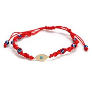 Detailed close-up of woven red cord bracelet with Evil Eye beads and golden metal eye charm