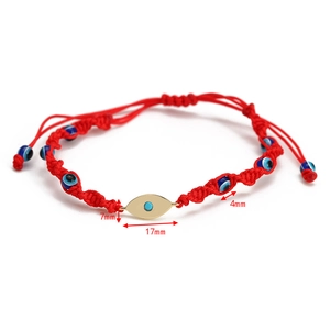 Detail view of woven red string bracelet with blue evil eye beads and gold metal accents