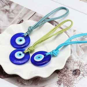 Close-up of glass Evil Eye nazar pendants with blue woven ropes on a ceramic plate