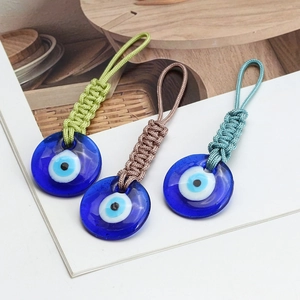 Handmade woven rope Evil Eye keychains with blue glass charms on a decorative card