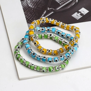 Detailed view of yellow, blue, and green evil eye beaded bracelets with crystal spacers