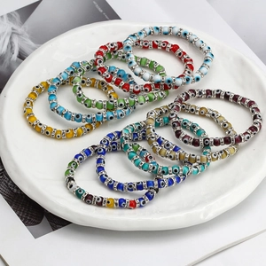 Colorful Evil Eye bead bracelets with rhinestone spacers in a white ceramic dish