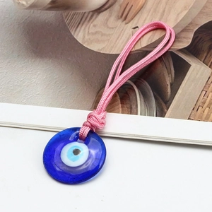 Blue glass evil eye charm with pink woven nylon cord on a clean white background