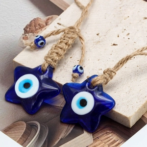 Detail of star-shaped blue glass evil eye pendants with rustic woven hemp rope tassels