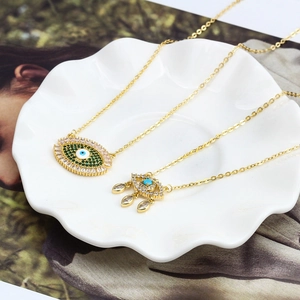 Gros plan détaillé des pendentifs Evil Eye dorés avec zircons verts et bleus incrustés