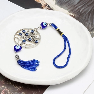 Porte-clés Arbre de Vie avec pendentif œil bleu et pompons sur assiette blanche