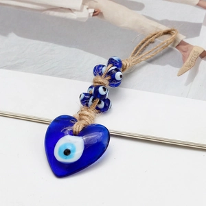 Detail of blue glass heart shaped Evil Eye pendant with braided rope on white backdrop