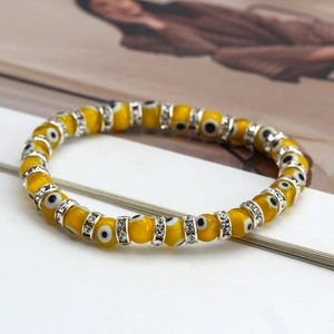 Macro shot of yellow resin evil eye beads with crystal spacers on a stretchy bracelet