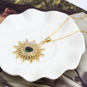 Détail du collier œil protecteur doré avec zircon vert sur une coupelle décorative