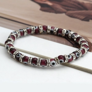 Detail of red beaded Evil Eye bracelet with silver zircon spacers on white background