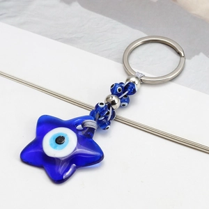 Detail of blue glass evil eye star keychain with beaded metal ring and braided rope