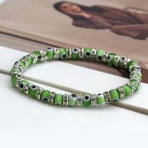 Detail of bohemian evil eye beaded bracelet with green eyes and crystal metal spacers