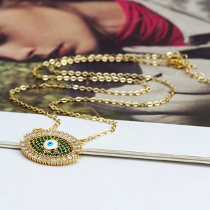 Vue macro d'un pendentif œil porte-bonheur doré serti de cristaux verts et zircons