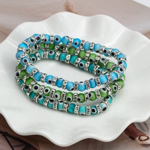 Close-up of Evil Eye beaded bracelets with rhinestones in a white ceramic dish