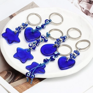 Set of 5 Evil Eye glass keychains with star and heart shapes in a white ceramic dish
