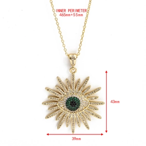 Détail du pendentif soleil doré serti de zircons blancs et oeil maléfique vert