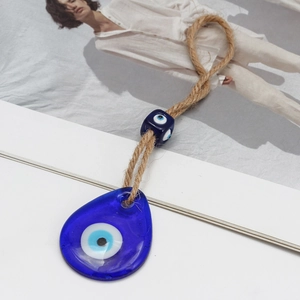 Detail of blue glass evil eye pendant with natural hemp rope and decorative square bead