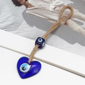 Macro shot of blue heart Nazar evil eye keychain charm with natural braided hemp rope
