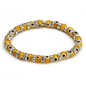 Macro detail of yellow evil eye beads with sparkling silver spacers on minimalist bracelet
