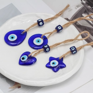 Detail of four blue glass evil eye charms in heart and star shapes with jute rope