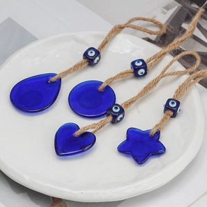 Detail of four blue glass Evil Eye charms in drop, heart, round and star shapes on jute ropes
