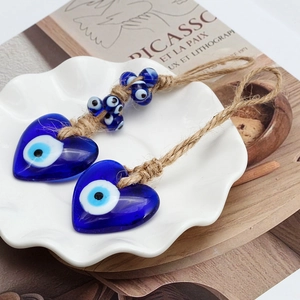 Blue heart evil eye glass pendant keychain with rustic hemp rope on artistic backdrop