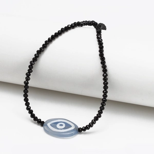 Detail of beaded evil eye bracelet with faceted black beads and blue eye charm