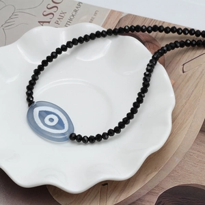 Ethnic style evil eye beaded necklace with black faceted crystals and blue pendant