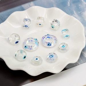 Macro detail of geometric Evil Eye crystal beads and faceted glass pendants in a tray