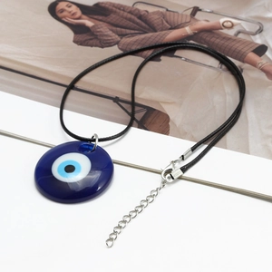 Λεπτομέρεια του σκούρου μπλε μενταγιόν Evil Eye με μαύρο κορδόνι και κούμπωμα καβουράκι