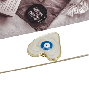 Macro shot of heart-shaped evil eye pendant with ivory enamel and gold-plated alloy trim
