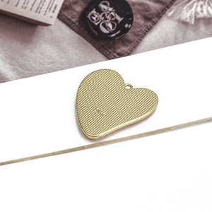 Golden heart-shaped pendant with devil eye texture and SW engraving on velvet background