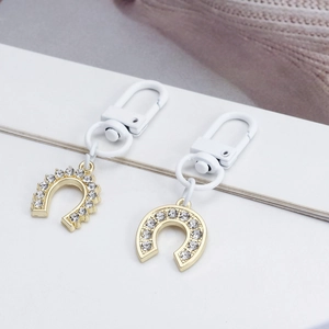 Two-piece gold horseshoe evil eye keychains with sparkling crystals and white hooks