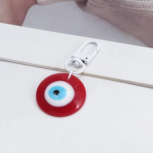 Macro shot of red round Evil Eye keychain featuring a white metal lobster clasp closure