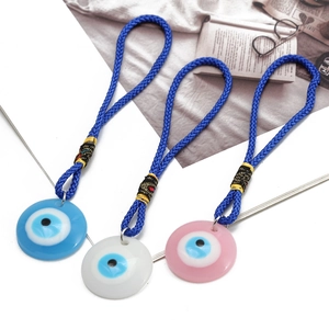 Detail of Turkish Evil Eye charms in light blue, white and pink with braided blue cord