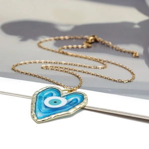 Dettaglio del ciondolo a forma di cuore malocchio con resina blu e catena in metallo dorato