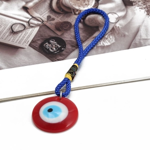 Detailed macro view of an Evil Eye charm with red resin pendant and blue braided cord
