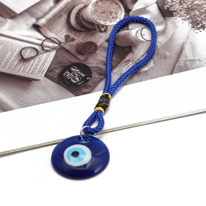 Close-up of Turkish evil eye pendant with blue glass charm and woven rope for car decor