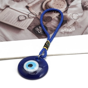 Close-up of a blue Evil Eye circular pendant with woven cord and decorative knot detail